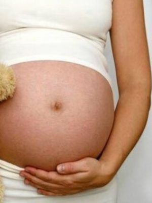 Mulher grávida segurando um urso de pelúcia.