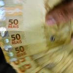 notas de 50 reais sendo seguradas | 13º salario