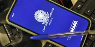 Carteira de trabalho digital no celulr com uma caneta em cima.