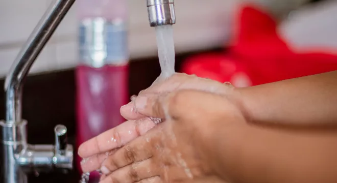 Mãos sendo lavadas em baixo da torneira