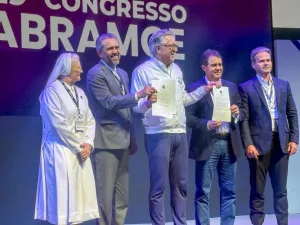 Elmano de Freitas, governador do Ceará, em pé ao lado de outras quatro pessoas segurando o termo que faz parceria com a iniciativa privada para a saúde.