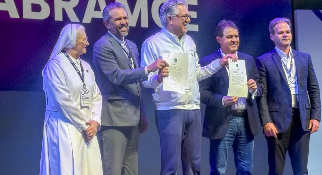 Elmano de Freitas, governador do Ceará, em pé ao lado de outras quatro pessoas segurando o termo que faz parceria com a iniciativa privada para a saúde.