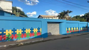 FACHADA DA CASA AZUL, EM MISSÃO VELHA MOSTR UM MRO AZUL COM DESENHOS E QUEBRA-CABÇA NAS CORES AMARELO, VERDE, AZUL ESCURO E VERMELHO.