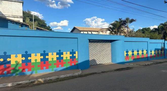 FACHADA DA CASA AZUL, EM MISSÃO VELHA MOSTR UM MRO AZUL COM DESENHOS E QUEBRA-CABÇA NAS CORES AMARELO, VERDE, AZUL ESCURO E VERMELHO.