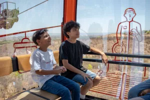 Duas crianças sentadas em passeio no Teleférico do Horto, em Juazeiro do Norte.