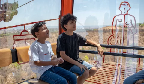 Duas crianças sentadas em passeio no Teleférico do Horto, em Juazeiro do Norte.