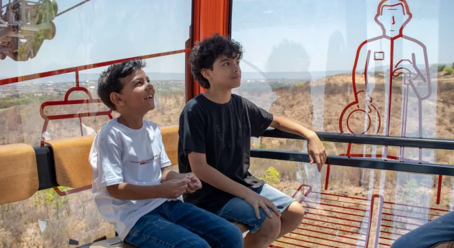 Duas crianças sentadas em passeio no Teleférico do Horto, em Juazeiro do Norte.