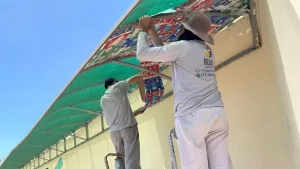 projeto cuca fresca no ponto de onibus do ifce em juazeiro do norte. a imagem mostra dois homens aplicando as mantas na parada de onibus.