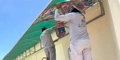 projeto cuca fresca no ponto de onibus do ifce em juazeiro do norte. a imagem mostra dois homens aplicando as mantas na parada de onibus.