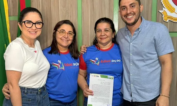 Assinatura do termo do projeto “Educação e Cidadania 2025”, de Várzea Alegre. A imagem mostra quatro pessoas, sendo três mulheres, da querda para a direita e um homem, que é o prefeito da cidade. Uma delas está segurando o papel.