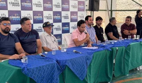 vereadores de juazeiro do norte durante edição do projeto "Câmara com o Povo". eles estão sentados em uma mesa coberta com tecidos azuis e verdes,
