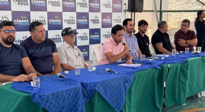 vereadores de juazeiro do norte durante edição do projeto "Câmara com o Povo". eles estão sentados em uma mesa coberta com tecidos azuis e verdes,