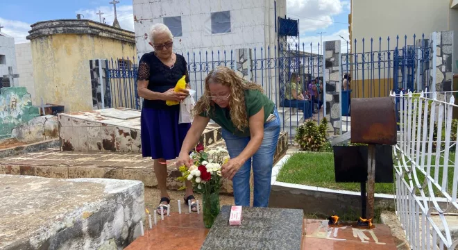 Duas mulheres colocando flores em cima de um jazigo durante o Dia de Finados em Juazeiro do Norte.