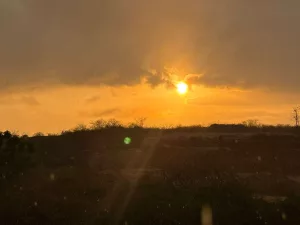 Imagem mostra o entardecer no Ceará. O céu está alaranjado e com temperatura que varia de 35ºC a 39º C.