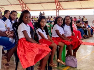 quatro crianças sentadas durante o lançamento do projeto raizes quilombolas, em salitre. todas estão de blusa branca e saias vermelhas.