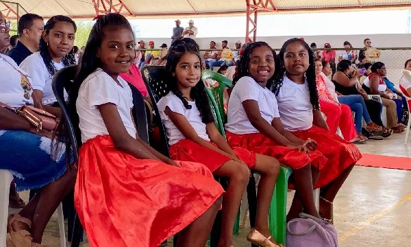 quatro crianças sentadas durante o lançamento do projeto raizes quilombolas, em salitre. todas estão de blusa branca e saias vermelhas.