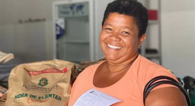 Mulher recebendo as sementes do Programa Hora de Plantar.