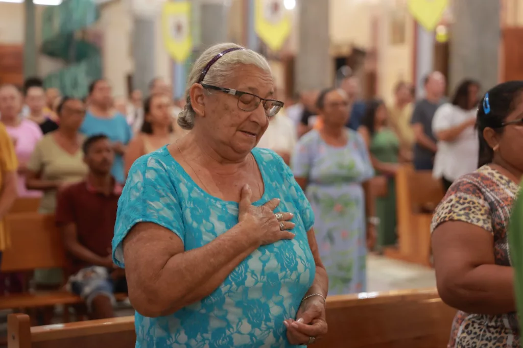 Mulher orando durante a romaria de candeias, dentro da igreja.