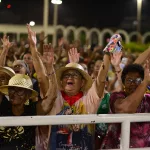Mulher em multidão orando durante a Romaria de Candeias.