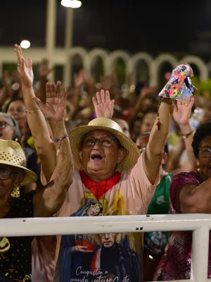 Mulher em multidão orando durante a Romaria de Candeias.