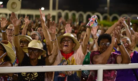 Mulher em multidão orando durante a Romaria de Candeias.