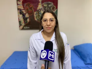 Ângela Rolim, fisioterapeuta intensivista do Hospital Santo Antônio, em Barbalha. A imagem mostra ela em frente a canopla no M1, durante entrevista para falar sobre Alzheimer.