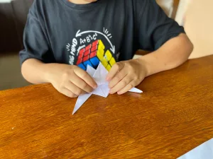 Aluno autista brincando com origami.