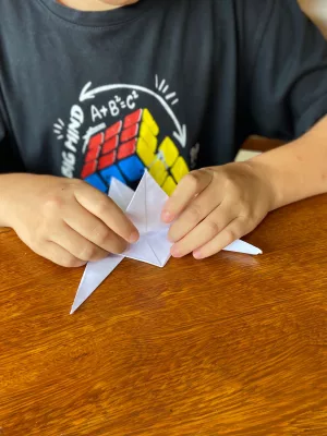 Aluno autista brincando com origami.