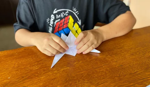 Aluno autista brincando com origami.