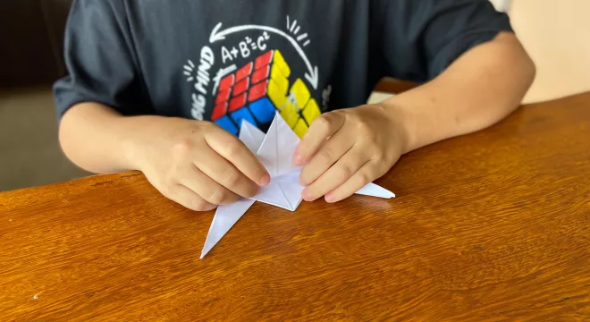 Aluno autista brincando com origami.