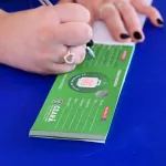 pessoa recebendo o vale gás. a imagem está focada nas mãos