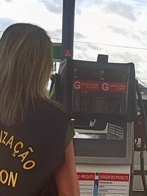 Fiscalização do decon em estabelecimentos da região do Cariri. A foto mostra uma mulher de costas fiscalizando um posto de gasolina.