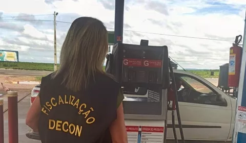 Fiscalização do decon em estabelecimentos da região do Cariri. A foto mostra uma mulher de costas fiscalizando um posto de gasolina.