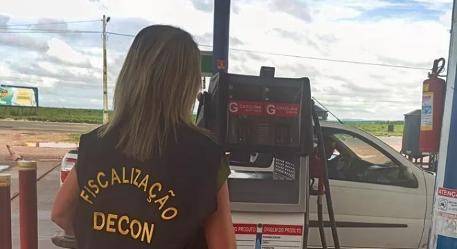 Fiscalização do decon em estabelecimentos da região do Cariri. A foto mostra uma mulher de costas fiscalizando um posto de gasolina.